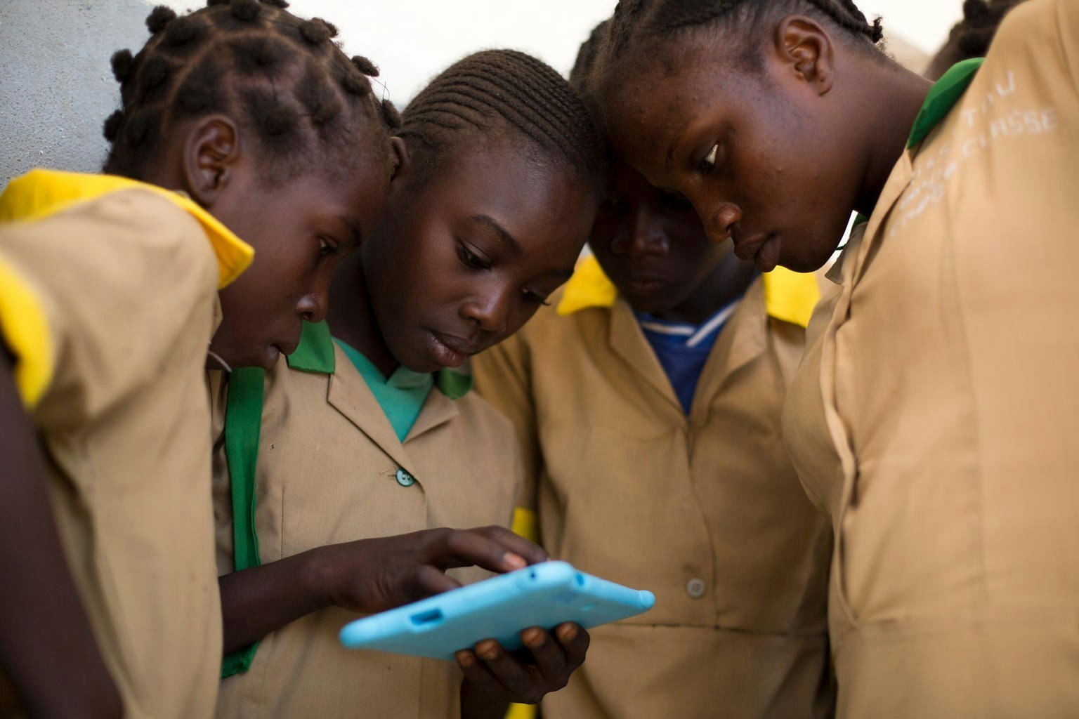 Children gathered around an ipad, benefiting from UNICEF Partnership's initiative to connect all schools